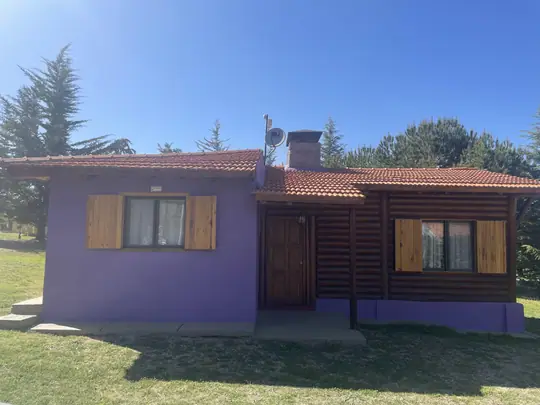 Cabaña Borgoña: fachada violeta con ventanas y puerta de madera