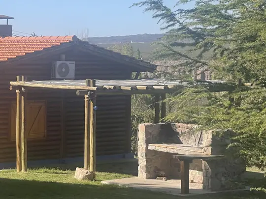 Vista lateral de una cabaña con su pérgola de madera
