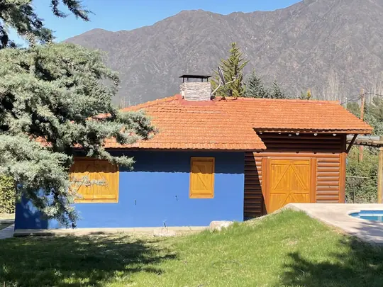 Cabaña Malbec: la cabaña junto a un pino alto y los cerros