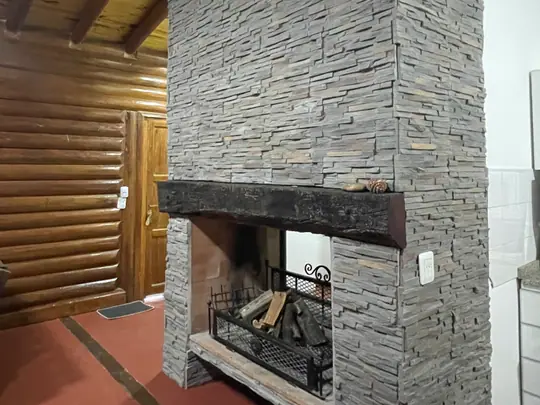 Interior con chimenea revestida en piedra y paredes de troncos