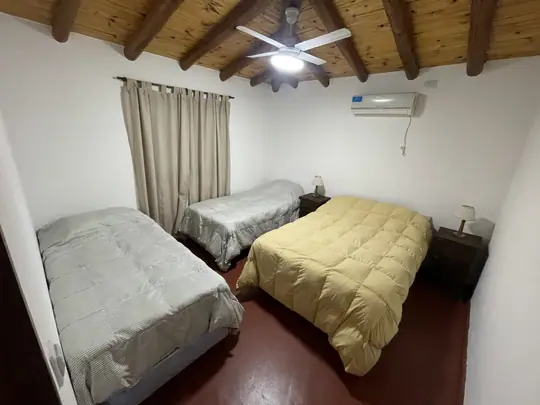 Dormitorio con camas tendidas, ventilador de techo y split