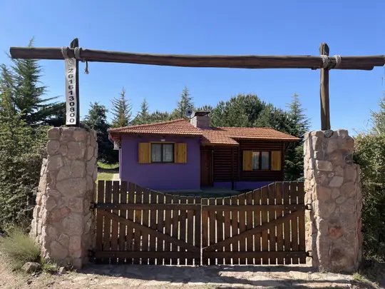 Tranquera de madera y pilares de piedra en el ingreso a la cabaña Borgoña